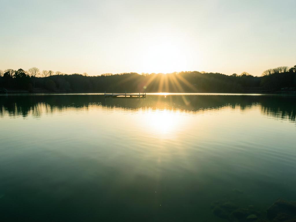 First light over a still lake with a small dock